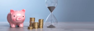 Üzerinde bozuk para ve kum saati olan kumbara.