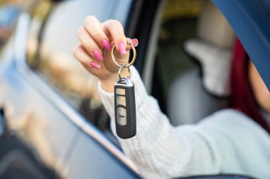 Arabanın camından araba anahtarı çıkartıp yeni bir araba alan bir kadın.