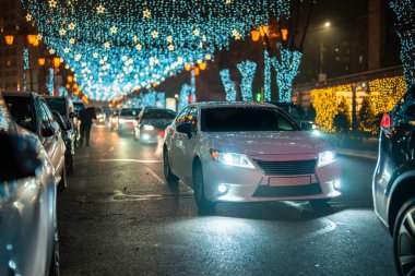 Noel ışıkları yolda takılıyor, arabalar yoldan geçiyor.