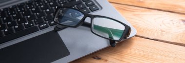 Tahta masada dizüstü bilgisayarı olan seçici odaklı gözlük.