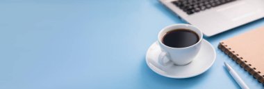 Dizüstü bilgisayarı, kahve fincanı ve not defteri olan ofis masası.