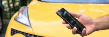 Bulanık araba geçmişi olan cep telefonu kullanan genç bir adam.