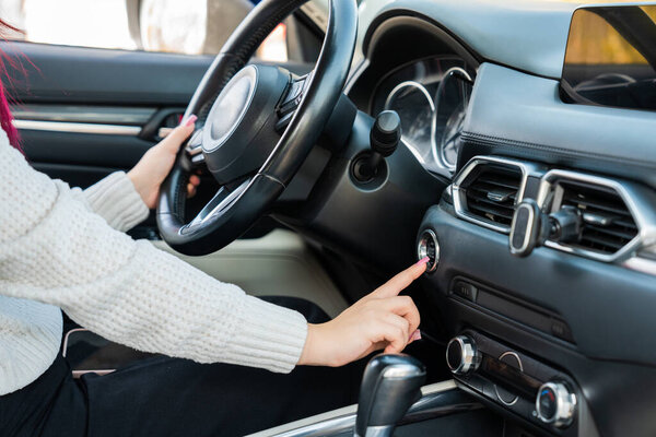 The female driver is trying to start the car's engine.