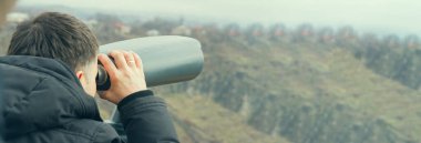Turist uzun dürbün manzarasına bakar.