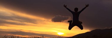 Gün batımında zıplayan bir çocuğun silueti..