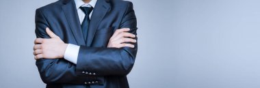 Kollarını kavuşturmuş bir takım elbise giyen zarif erkek modelin yakın plan portresi..