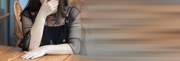 Closeup of young woman at cafe covering mouth with hands