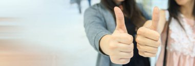 Baş parmaklarını gösteren iki genç kızın yakın çekimi..