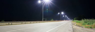 Geceleri sokak lambaları olan boş kırsal yol. 
