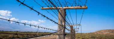 Mavi bulutlu arkaplanda dikenli tel örgü. 