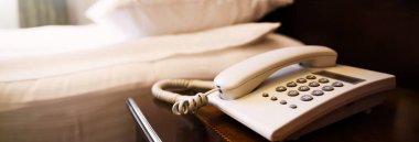 Yatak yastıkları ve telefonlu otel odası sahnesi.