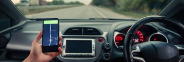 Elinde seyir subayı olan bir telefon tutuyor.