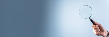 Gri sırtüstü büyüteç tutan genç kadın.