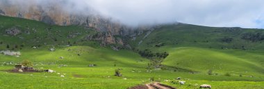 Toprak yol bulutların altındaki dağlara çıkar.