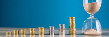 Bozuk paralar ve kum saatleri ahşap masada.