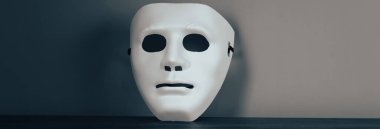 Ahşap bir masada isimsiz beyaz bir maske