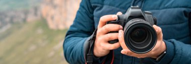 Adam dağda elinde bir kamera tutuyor.