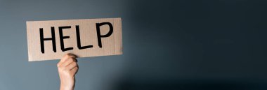 Üzerinde yazı olan bir karton parçası tutan eller. Gri bir sırt grubunda yardım.