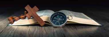 Kitap, haç ve pusula masanın üzerinde. Worldview yön göstergesi