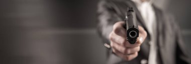 Takım elbiseli bir adam kancaya silah doğrulttu.