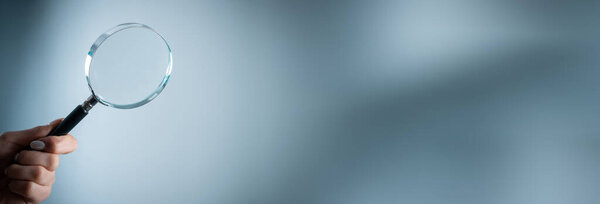 Holding a magnifying glass on a gray backgroun