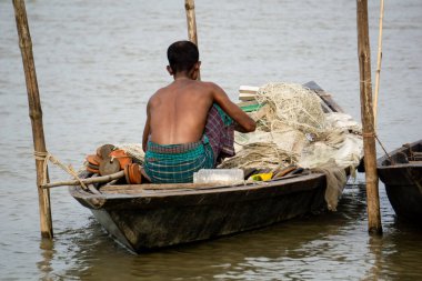 Gorai-Madhumati Nehri. Nehirde bir balıkçı teknesi. Bir balıkçı teknedeki balık ağını tamir ediyor. Sahne 24 Ekim 2023 tarihinde Rajbari, Bangladeş 'te çekildi..