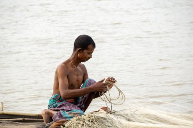 Gorai-Madhumati River. Fishing boat in the river. A fisherman is fixing the fishing net on the boat. The scene was captured on 24 October 2023 from Rajbari, Bangladesh. clipart