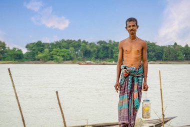 Bangladeş 'in Riverside halkı. Bir balıkçı nehir kıyısının arkasındaki alacakaranlık ufkunda duruyor..