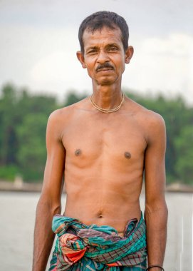 Bangladeş 'in Riverside halkı. Bir balıkçı nehir kıyısının arkasındaki alacakaranlık ufkunda duruyor..