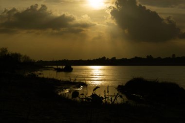 Bangladeş 'in Gorai-Madhumati nehri. Nehirde akşam yemeği. Balıkçı tekneleri nehir kıyısında bağlı. Nehir alacakaranlık gökyüzünün altından akar..