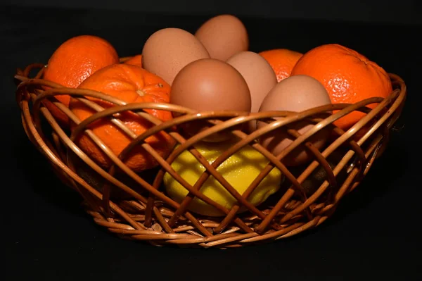 easter holiday, eggs, fruits in  basket on black background