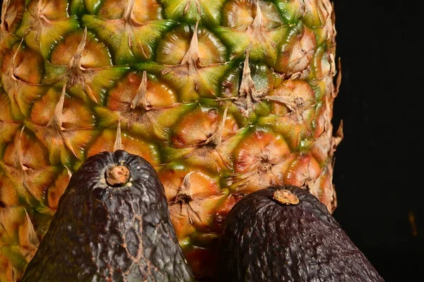 pineapple  and avocados on a black background