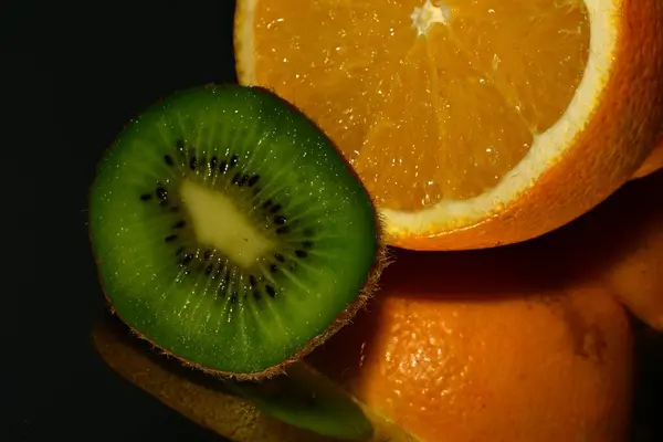 kiwi and orange fruits on black background
