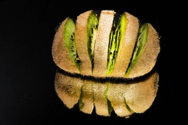 Siyah arkaplanı olan taze bir kivinin kapağı.