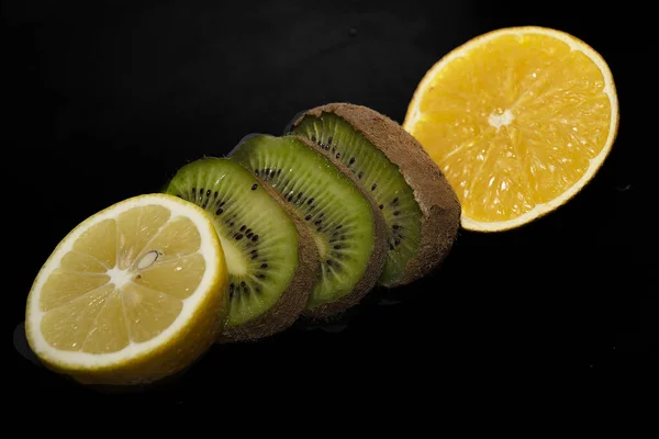 sliced kiwi and lemon slices on black background