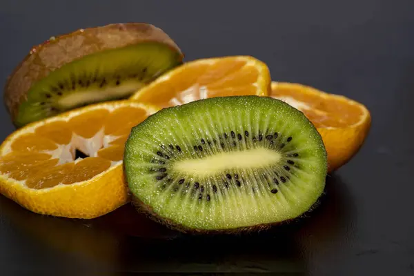fresh cut orange and kiwi slices on black background.