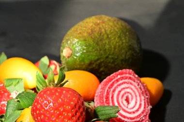 Siyah arka planda sarılmış jöleli bir grup meyve.