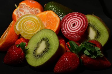 Siyah arka planda sarılmış jöleli bir grup meyve.