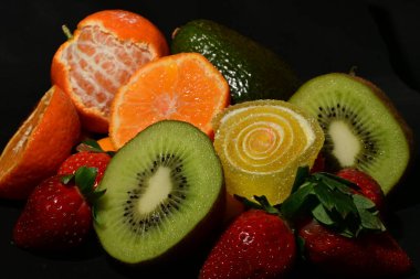 Siyah arka planda sarılmış jöleli bir grup meyve.