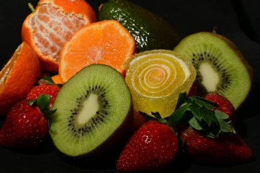 Siyah arka planda sarılmış jöleli bir grup meyve.