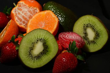 Siyah arka planda sarılmış jöleli bir grup meyve.