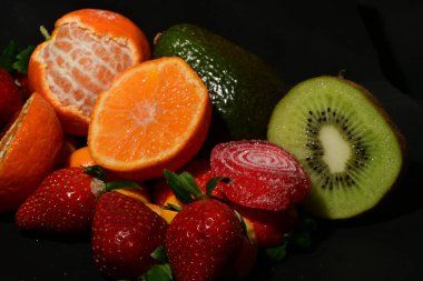 Siyah arka planda sarılmış jöleli bir grup meyve.