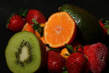 Siyah arka planda sarılmış jöleli bir grup meyve.