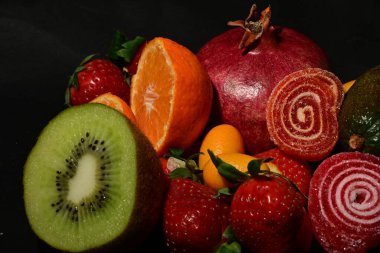 Siyah arka planda sarılmış jöleli bir grup meyve.