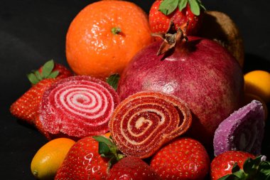 Siyah arka planda sarılmış jöleli bir grup meyve.