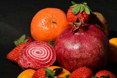 Siyah arka planda sarılmış jöleli bir grup meyve.