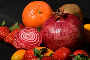 Siyah arka planda sarılmış jöleli bir grup meyve.