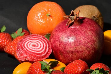 Siyah arka planda sarılmış jöleli bir grup meyve.