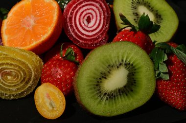 Siyah arka planda sarılmış jöleli meyve ve sebze çeşitleri