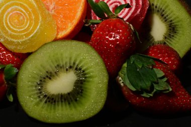 Siyah arka planda sarılmış jöleli meyve ve sebze çeşitleri